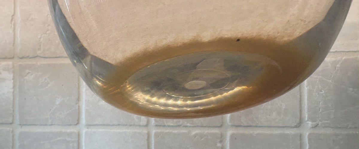 Amber sediment settled across the floor of the pitcher, seen through the glass.