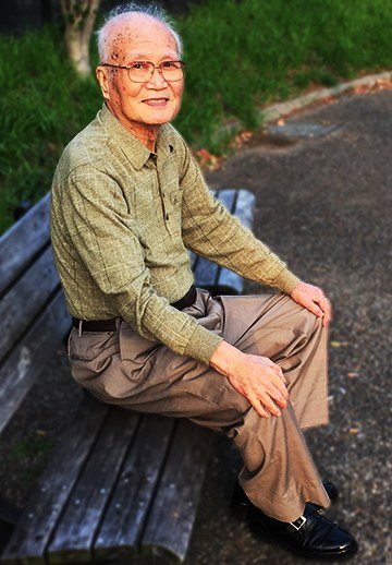 Asao Shimanishi seated on a park bench.